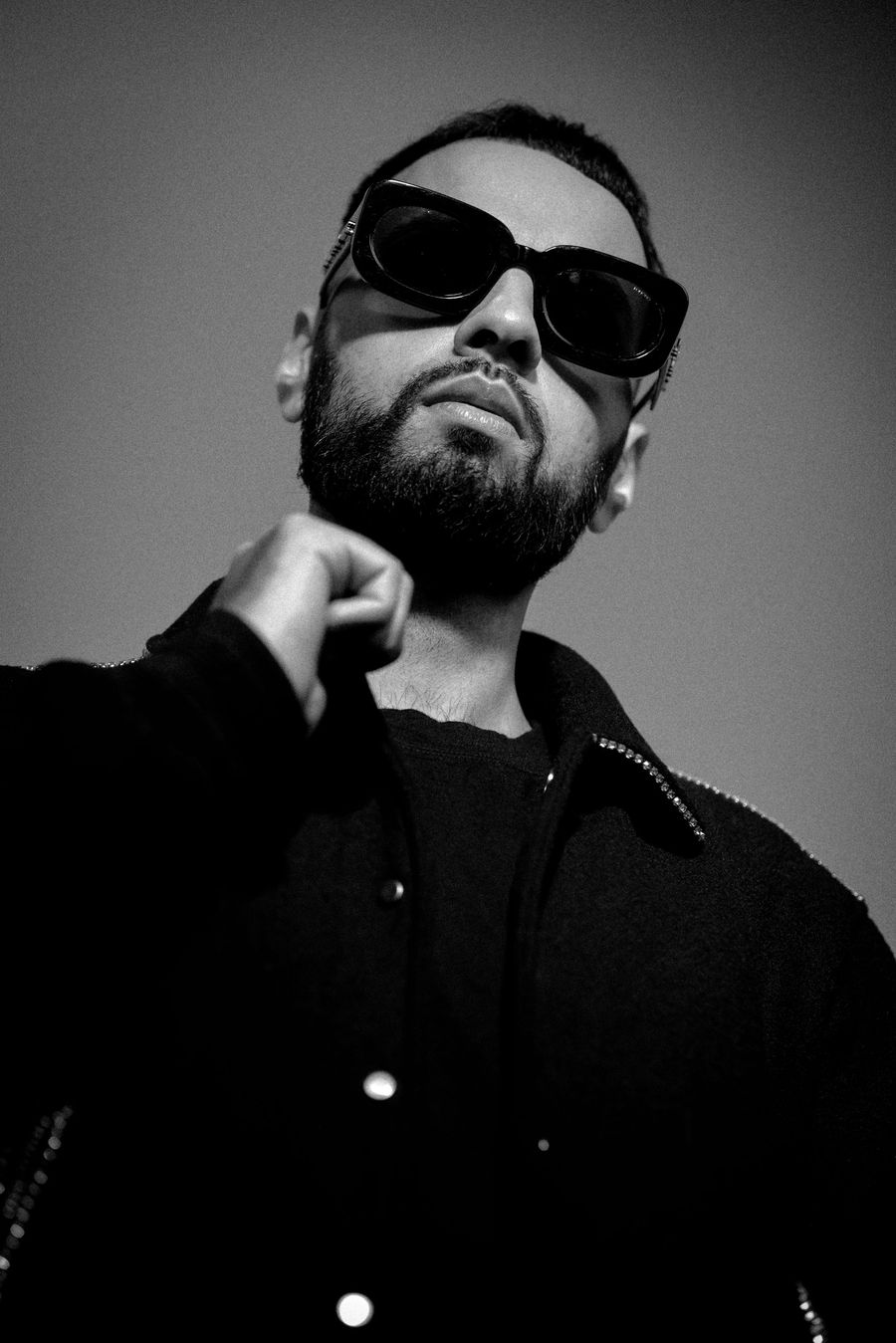 DJ Rish in sunglasses and a crystal-trimmed jacket, photographed from below