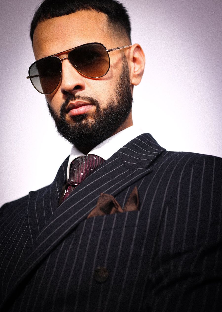 DJ Rish in a navy pinstripe suit and aviators